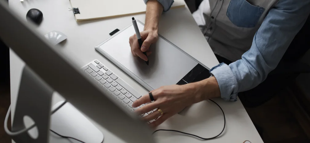 Designer working at a desk using a graphic tablet and computer to create digital ad visuals