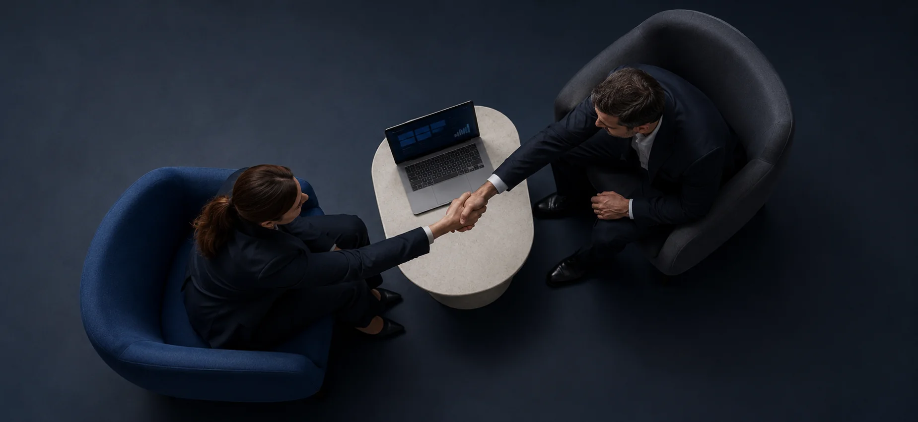 Two business professionals shaking hands beside a laptop displaying PPC campaign analytics