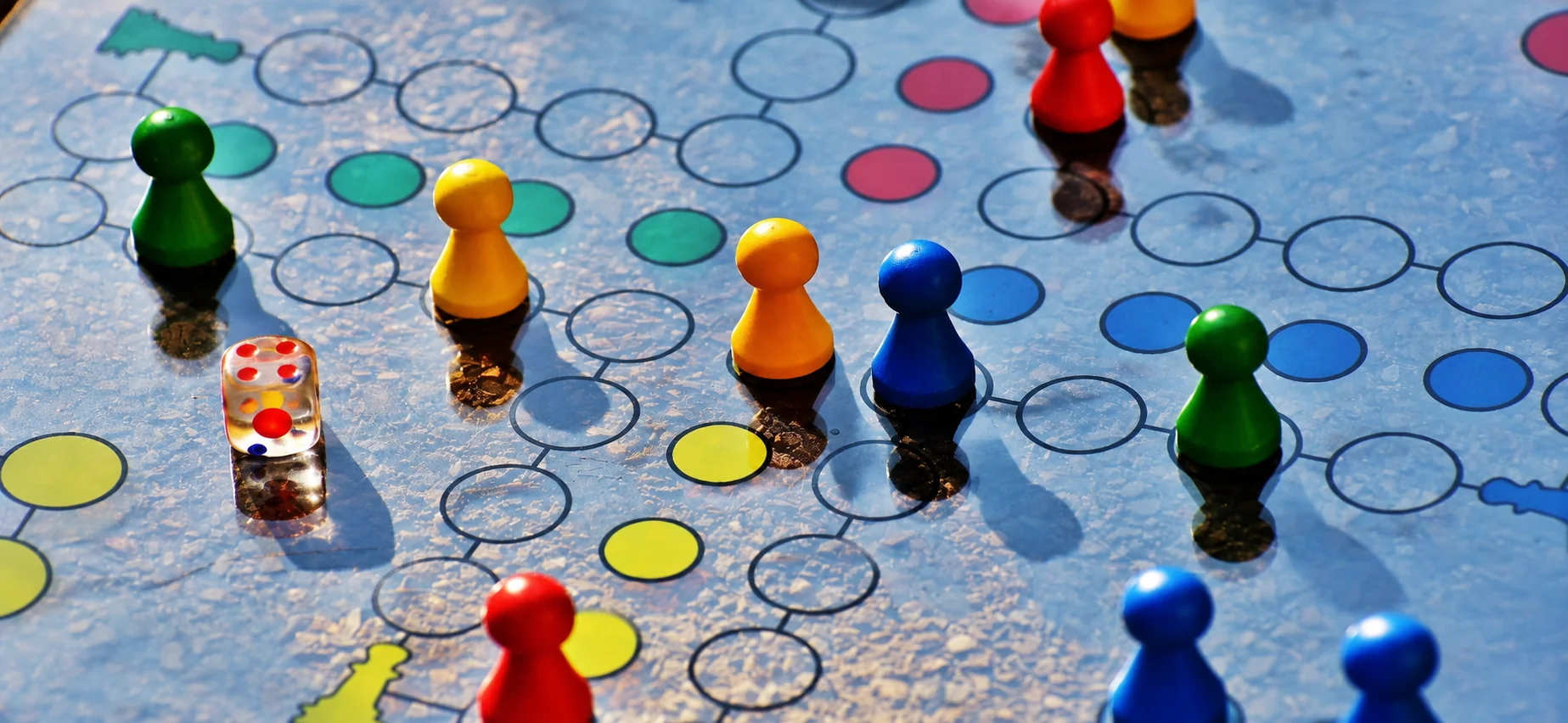 Colorful board game pieces and dice on a game board with circular spaces.